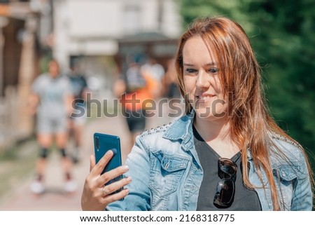 girl on the street with mobile phone recording or making selfie