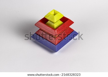 Creative colorful isolated 3D object pyramid like made out of plastic cubic shapes against white background with shadows. Top side view.