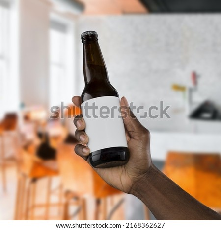 hand holding a beer bottle with black label on restaurant cafe pub background Royalty-Free Stock Photo #2168362627