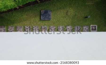 A garden of green grass, bamboo, square stepping stones, drainage, and lights is visible from above. White walls can be used for text or background designs. Top view.