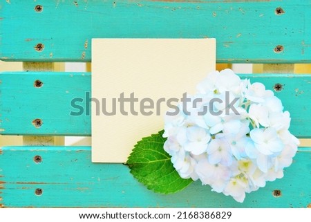 A mockup of the comment space with a whitish blue hydrangea against a background of a vintage-style green board with nails.