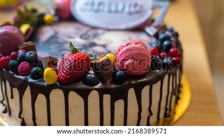 A cake for a children's birthday with berries, fruits, macaroons, depicting a cute Persian kitten