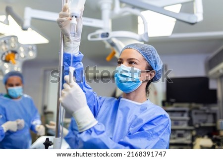 Female Doctor in the operating room putting drugs through an IV - surgery concepts