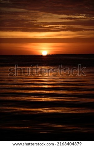 Gold sky and sea water. Sunset with large yellow sun under the sea surface. Calm ocean with sunset sky and sun through the clouds over. Calm ocean and sky background.