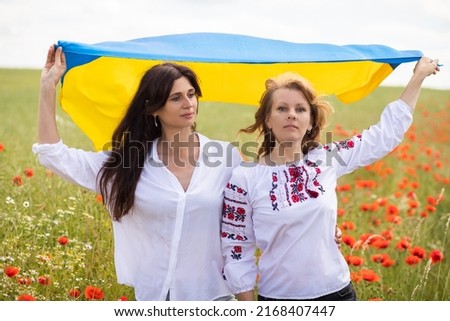 The flag of Ukraine in the hands of young women, the flag flutters over the field, the war in Ukraine, patriotism, defense of the motherland, faith in victory.