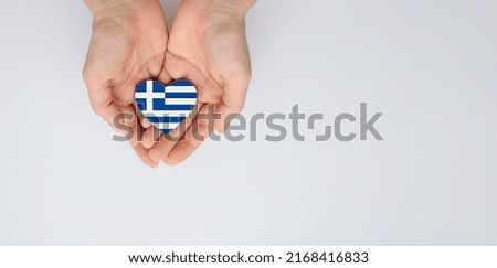 The national flag of Greece of arms in female hands. Flat lay, copy space.