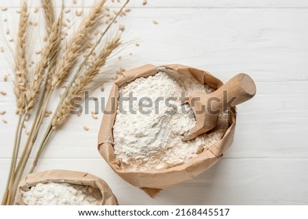 Bags with wheat flour on white wooden background, closeup Royalty-Free Stock Photo #2168445517