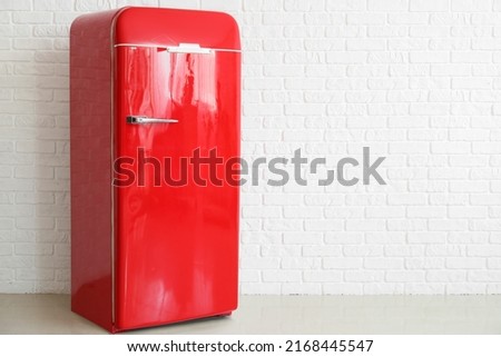 Stylish retro fridge near light brick wall in room