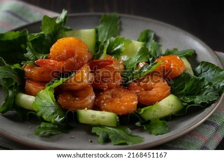 Fresh salad with grilled shrimps, cucumbers and arugula beautifully served on a plate