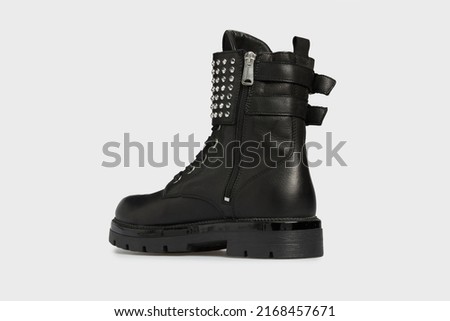 Back view on black women's fashion combat boots isolated on white background. Female classic spring autumn shoes. Leather casual footwear with metal rivets, spikes, buckle. Punk, emo, goth style