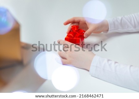 Closeup of Hands of Caucasian Female Holding Wrapped Red Gift Box Along with Batch of Present Boxes on Side. Horizontal Image