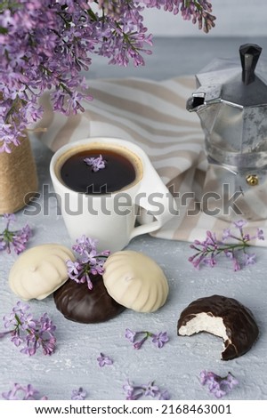 Cup of coffee, lilac, marshmallow in dark and white chocolate glaze, coffee maker. Still life
