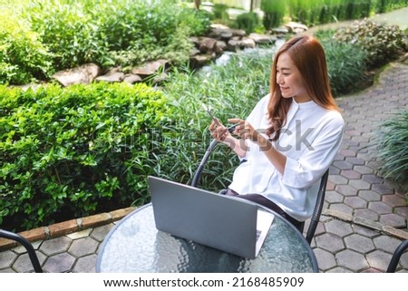 Portrait image of a businesswoman using mobile phone and working on laptop computer in the outdoors