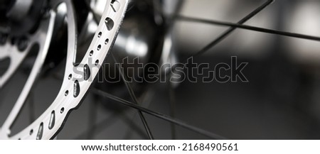 Hydraulic bicycle disk brakes, grey metal disc attached to bike wheel close up, effective popular mountain bicycle brakes. Hydraulic disk brakes on bicycle wheel, bicycle spokes gray background Royalty-Free Stock Photo #2168490561