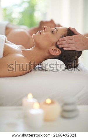 Enjoying a day of pampering. A husband and wife lying together on massage tables and receiving head massages. Royalty-Free Stock Photo #2168492321
