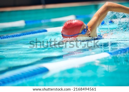 Working on her stroke. Shot of a professional female swimmer freestyle swimming in her lane. Royalty-Free Stock Photo #2168494561