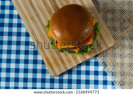 flat lay top view shot of cheeseburger on wooden surface.