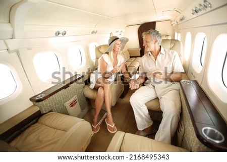 First-class all the way. Smiling and happy couple seated in a private jet and toasting each other while heading on a trip. Royalty-Free Stock Photo #2168495343