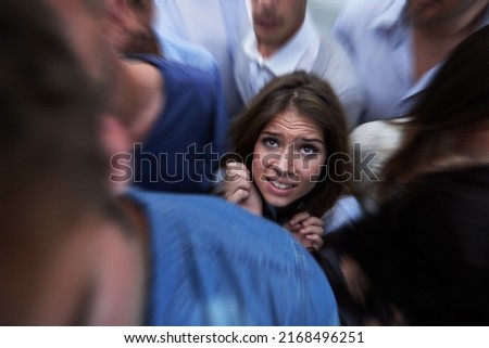 Drowning in people. Shot of a fearful young woman feeling trapped by the crowd. Royalty-Free Stock Photo #2168496251