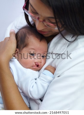 Giving comfort is key in her profession. Shot of a young female nurse holding a baby who has a cleft palate. Royalty-Free Stock Photo #2168497051