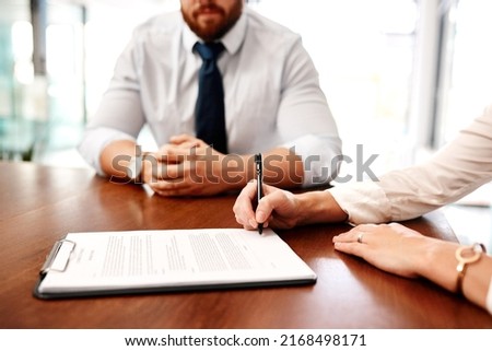 Sitting down to sign an agreement between two parties. Closeup shot of two businesspeople going through paperwork together in an office.