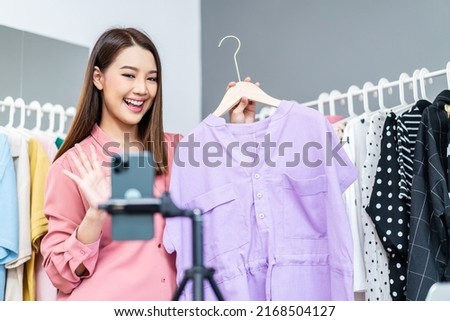 Young asian woman business owner at fashion store wave hello smartphone live streaming for sale fashion clothing to customer and present detail on social media, Online shopping concept. Royalty-Free Stock Photo #2168504127