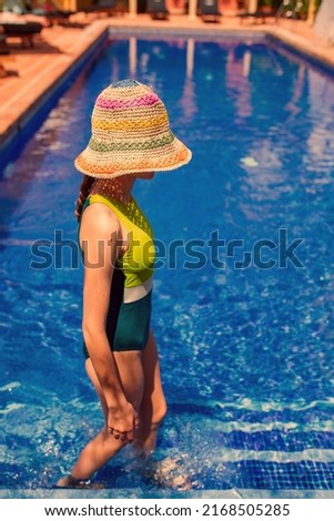 White slim girl in swimsuit and colorful panama. Outdoor fresh vibe near pool. Summer hot day in Spain vocation.
