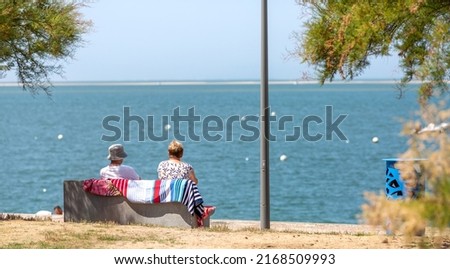 couple sitting on a bench looking at the sea