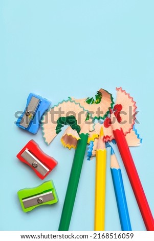 Top view of colored pencils, pencil sharpener and pencil shavings with space for text on blue background. Back to school concept