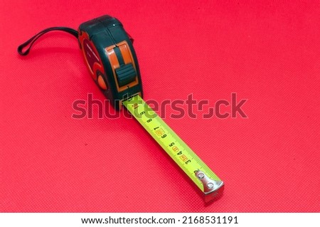 Symbol picture measure: roll up metal tape measure, cut out on red background