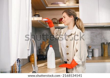 Woman in red gloves is doing housekeeping and wiping a furniture