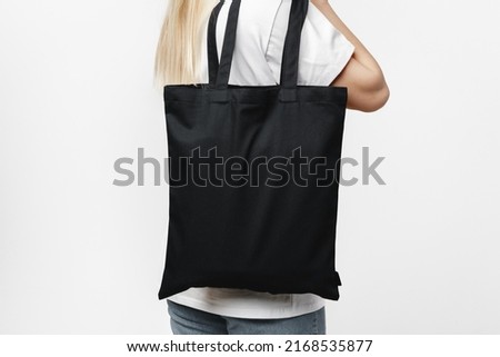 Female holding black cotton bag in her hands on white background, close up Royalty-Free Stock Photo #2168535877