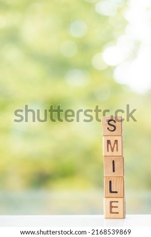 Smile word is written on wooden cubes on a green summer background Closeup of wooden elements