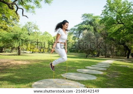 Young indian fitness woman wearing white sportswear skipping rope at park , Asian female Jumping exercise outdoor, Summer activity.  Royalty-Free Stock Photo #2168542149