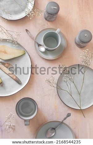 Empty grey uneven ceramic dish collection on a light pastel peach pink table with cutlery, candles and other decorative elements Royalty-Free Stock Photo #2168544235