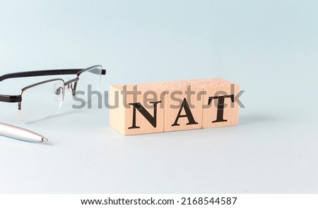 Text NAT Network Address Translation - written on the wooden cubes on a blue background