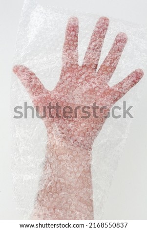 Male hand inside a transparent wrap bag. Hand of a male wrapped in protective plastic film with bubble.
