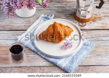 Croissant on a white plate and black coffee on a background with