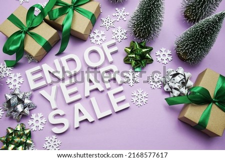 End of Year Sale alphabet letters with gift boxes, snowflake and artificial christmas tree on purple background