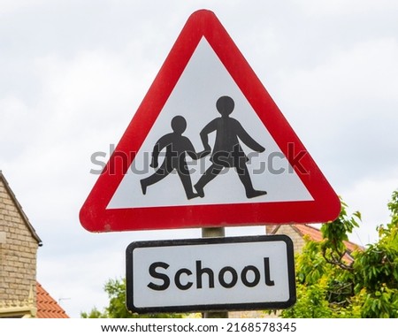 A road sign cautioning drivers that children could be crossing the road, near a school in the UK.