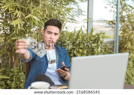 A wealthy and pompous man gives a large tip while browsing on his phone. Remote working at an outdoor cafe or coffee shop. Royalty-Free Stock Photo #2168586545