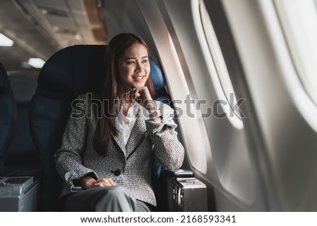 beautiful young asian woman sits in a plane and looking outside Royalty-Free Stock Photo #2168593341