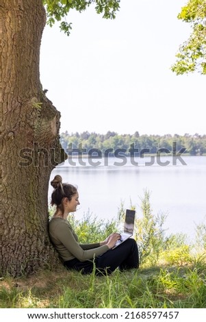 Work from anywhere. Remote freelancer work in nature. Young woman, female freelancer working with laptop with Beautiful view of forest and lake. freelancer paradise, freedom of teleworking. distance Royalty-Free Stock Photo #2168597457