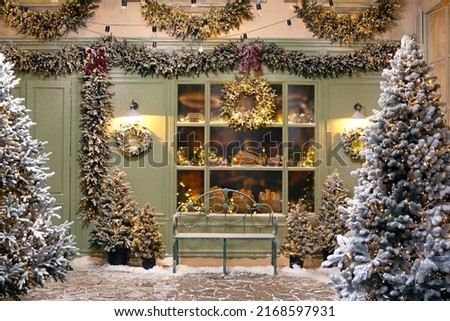 New Year's photo zone with snow near a cafe bakery.
Christmas decor: toys, Christmas trees, bench, garland, glowing light bulbs. festive mood. picture for postcard