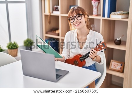 Young woman having online ukelele class at home