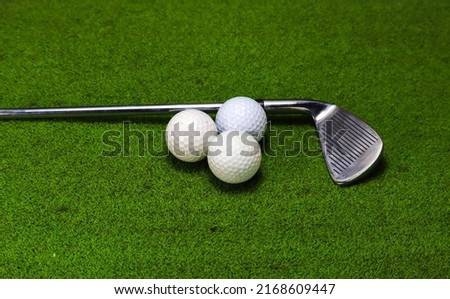 Golf balls and golf clubs placed on green grass
