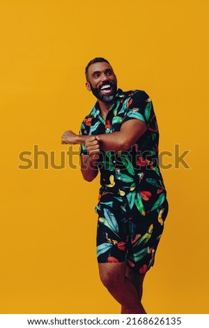 handsome bearded mid adult african american man smiling and dancing wearing Hawaiian shorts and shirt on vacation studio shot Royalty-Free Stock Photo #2168626135