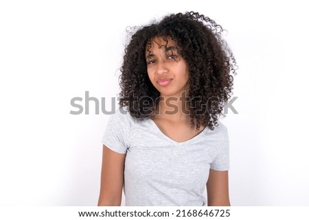 Displeased Young beautiful girl with afro hairstyle wearing grey t-shirt over white background frowns face feels unhappy has some problems. Negative emotions and feelings concept