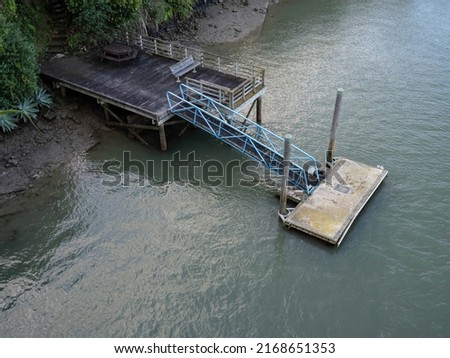 Floating concrete jetty with metal bridge and wooden piles. Aerial view. Stock photo.