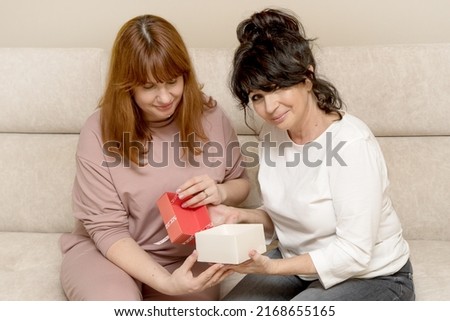 two woman, mother and daughter give gifts to each other and consider them, the concept of giving gifts, family holidays.